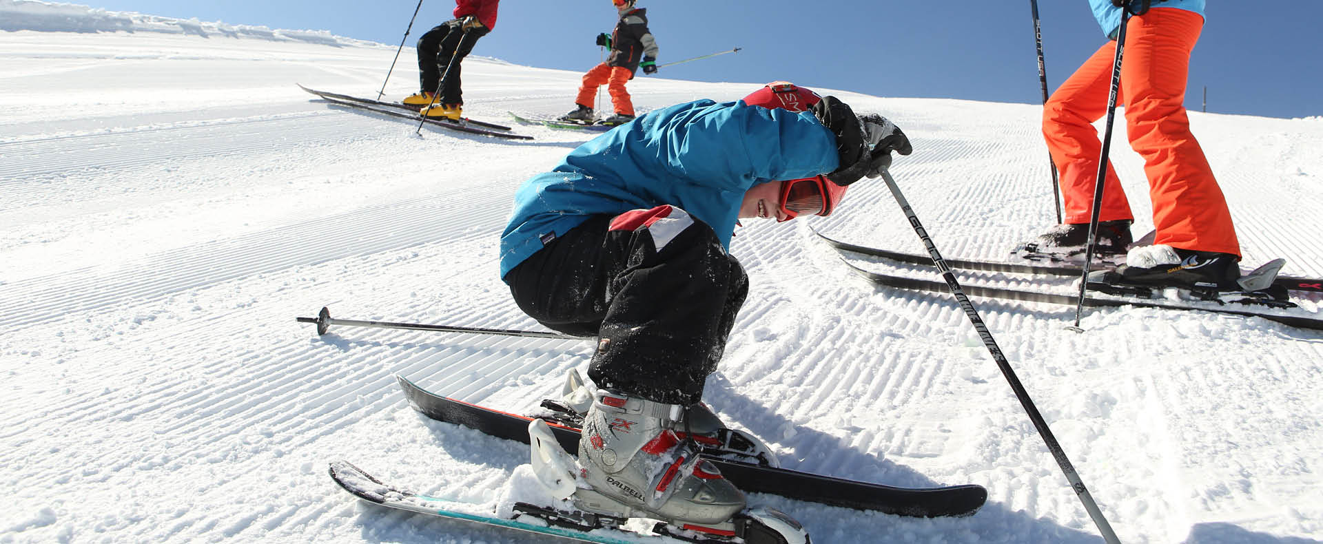 Child downhill skiing getting back up from a fall with a smile.